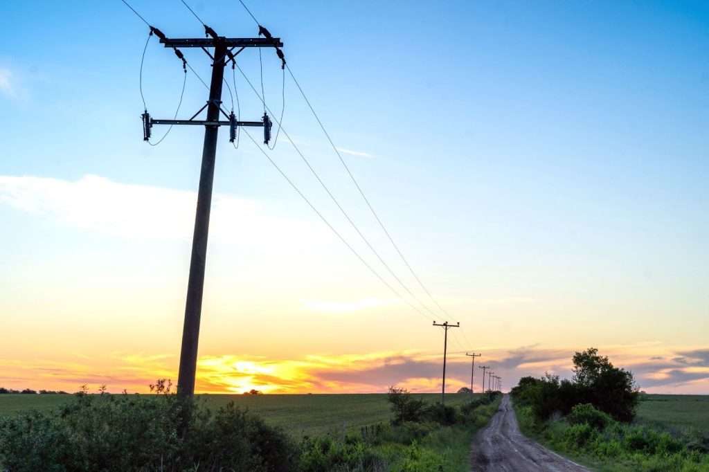 Power lines across a agricultural land, highlighting the potential of solar powered water pumps to reduce energy costs for farmers.